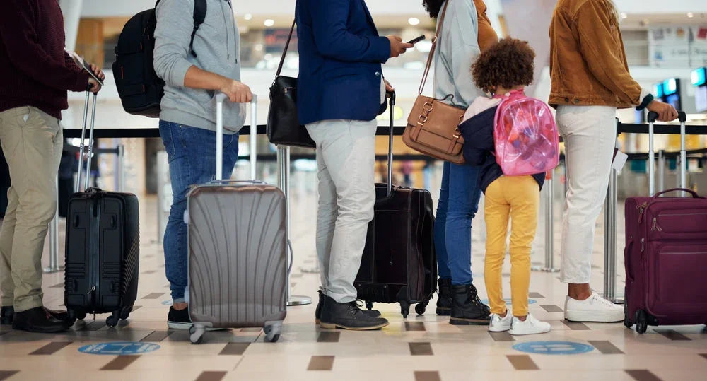Travelers standing in airport queue with suitcases and a child wearing a pink backpack