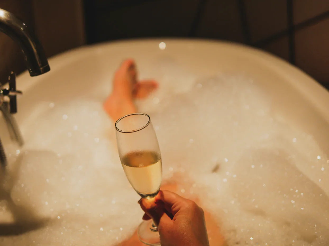 Relaxing bubble bath with a hand holding a glass of champagne