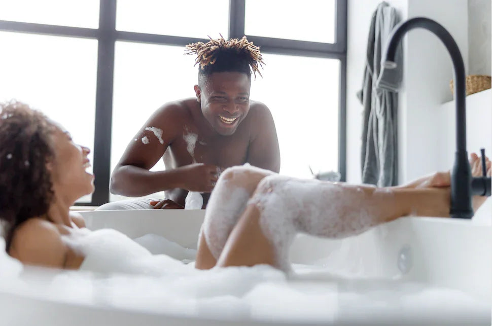 Young couple enjoying a playful bubble bath together in a bright modern bathroom