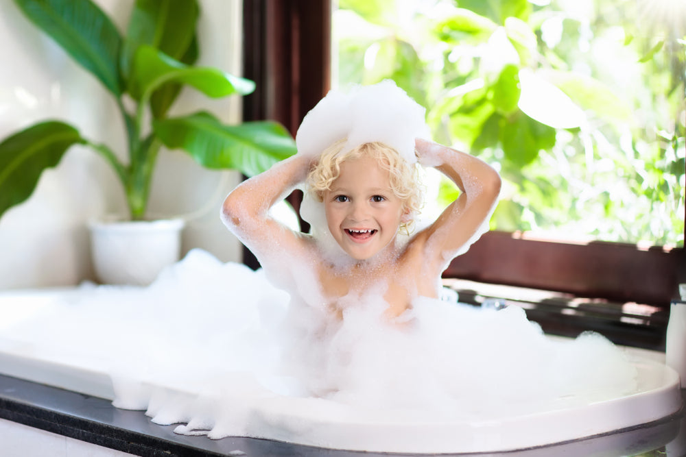 Little child taking bubble bath in beautiful bathroom