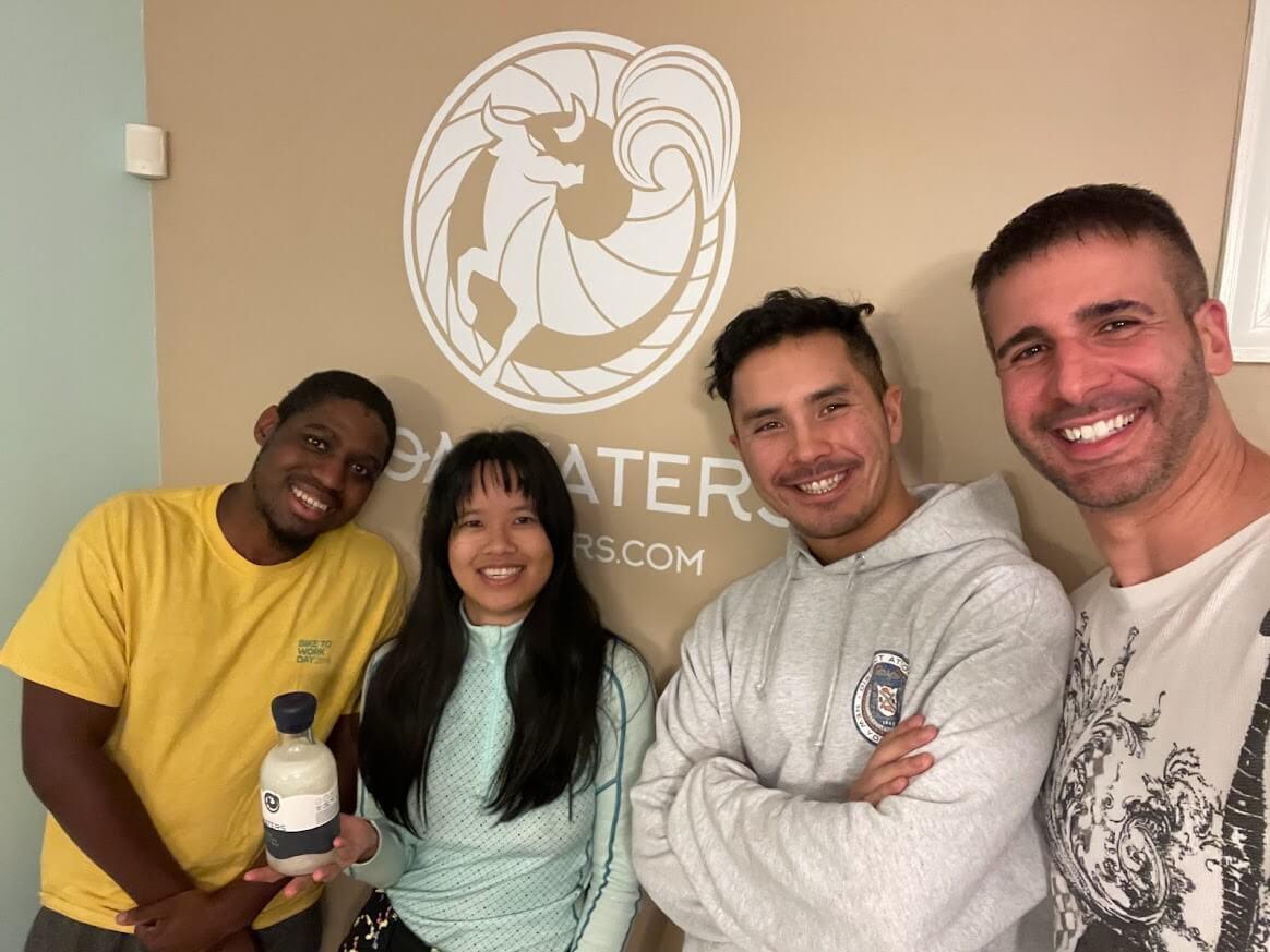 Friends pose in front of the TOA Waters sign with founder, Javier Folgar.