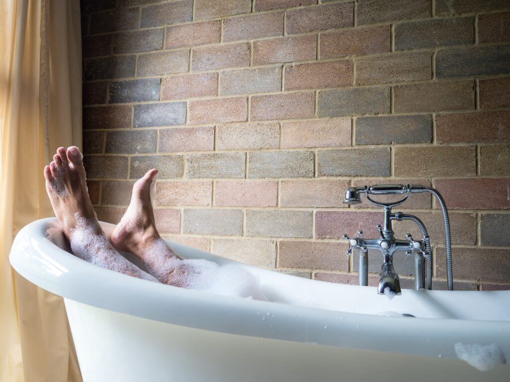 Man's feet handing out of his bubble bath