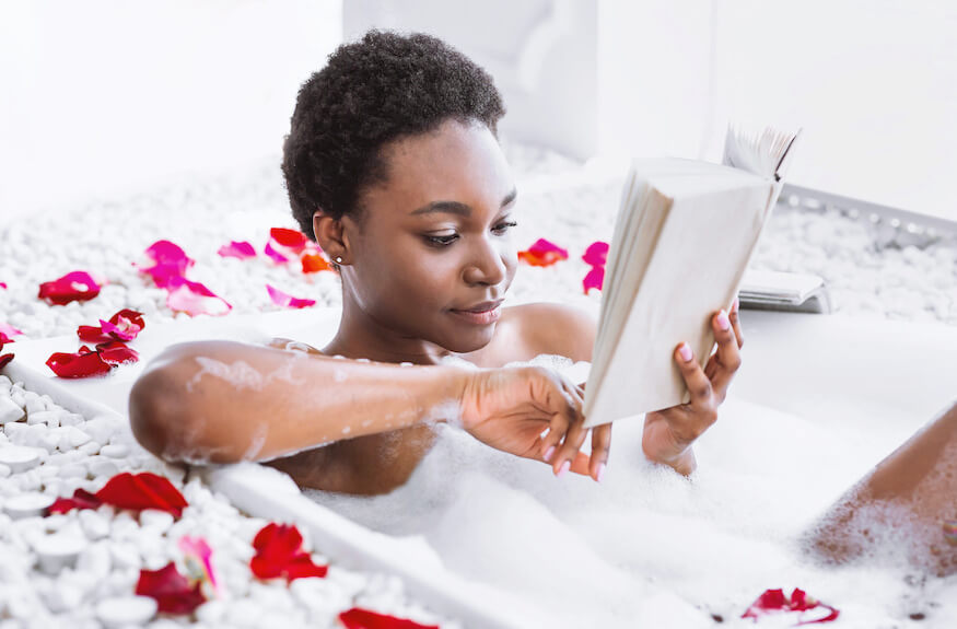 Woman reading while taking a bubble bath